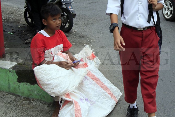 CONTOH : Ilustrasi anak tengah membawa karung yang melihat anak seusianya berseragam sekolah. (Dokumentasi Radar Malang)