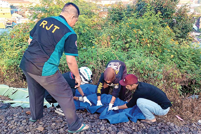 EVAKUASI: Relawan membungkus jenazah Firdaus yang tertabrak KA Brawijaya relasi Gambir-Malang di perlintasan kereta api KM 49 +8-9, Kelurahan Kesatrian, Kecamatan Blimbing, kemarin sore (11/6). (Relawan Malang Raya for Radar Malang)