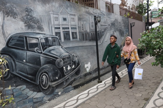 MULAI DIKUNJUNGI: Dua wisatawan berjalan di Kampoeng Heritage Kajoetangan, kemarin siang. Per hari, tercatat ada 200 hingga 500 wisatawan berkunjung ke sana. (darmono/radar malang)