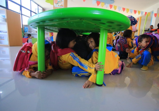 BELAJAR MITIGASI BENCANA: Sejumlah siswa PAUD Omah Bocah Annaafi’ latihan mitigasi bencana gempa dengan berlindung di kolong meja, kemarin pagi. (suharto/radar malang)