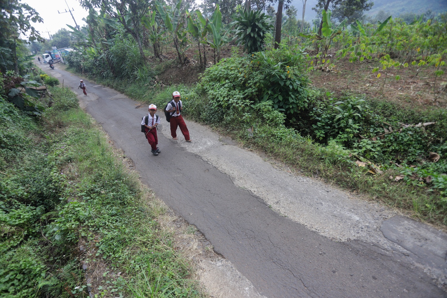 JALAN KE SEKOLAH: Sejumlah siswa melintasi jalan yang belum memadai di kawasan pinggiran Kabupaten Mojokerto.