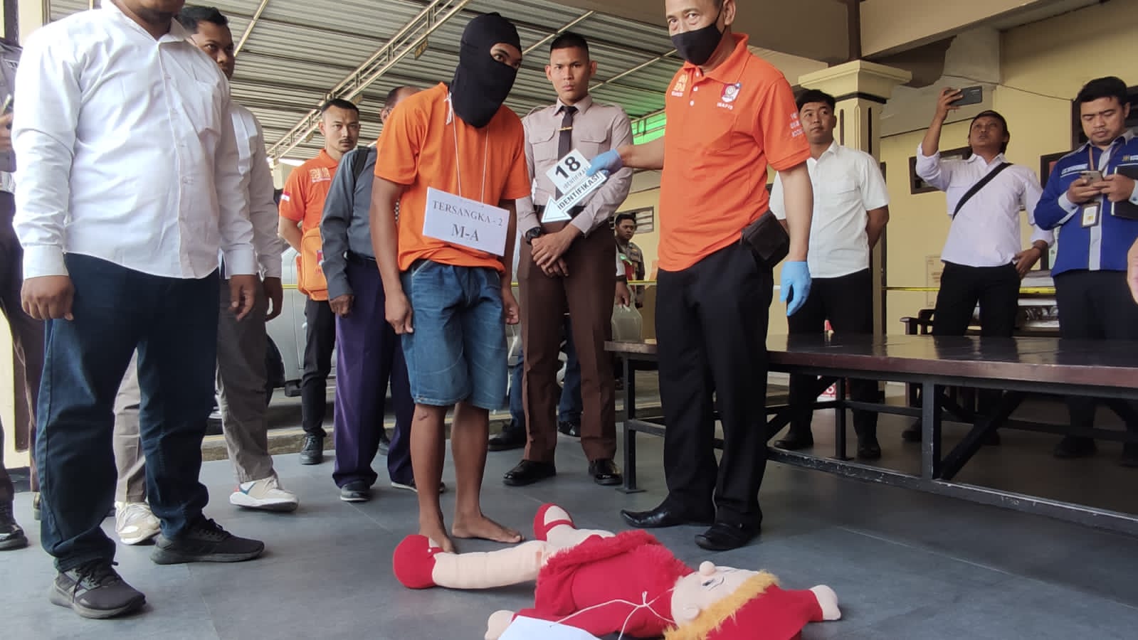 ADEGAN: MA, 19, dengan menggunakan sebo (penutup kepala) memeragakan salah satu adegan pada rekonstruksi kasus pembunuhan siswi SMP Kemlagi di Markas Polres Mojokerto Kota, Senin (19/6).