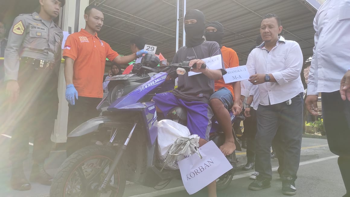 KEJAM: Kedua pelaku tampak memeragakan adegan membawa mayat korban dalam karung ditaruh motor hendak membuang ke sungai, saat rekonstruksi di markas Polres Mojokerto Kota, Senin (18/6).