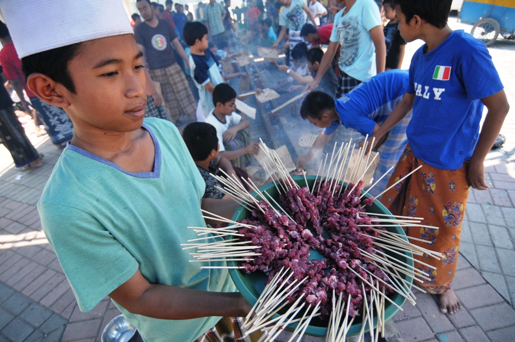 Seorang santri menunjukkan sate yang hendak dibakar.