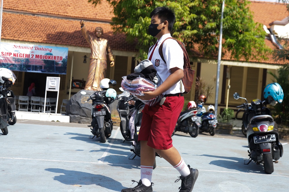 PERLENGKAPAN GRATIS: Seorang siswa tengah membawa bantuan perlengkapan sekolah gratis.