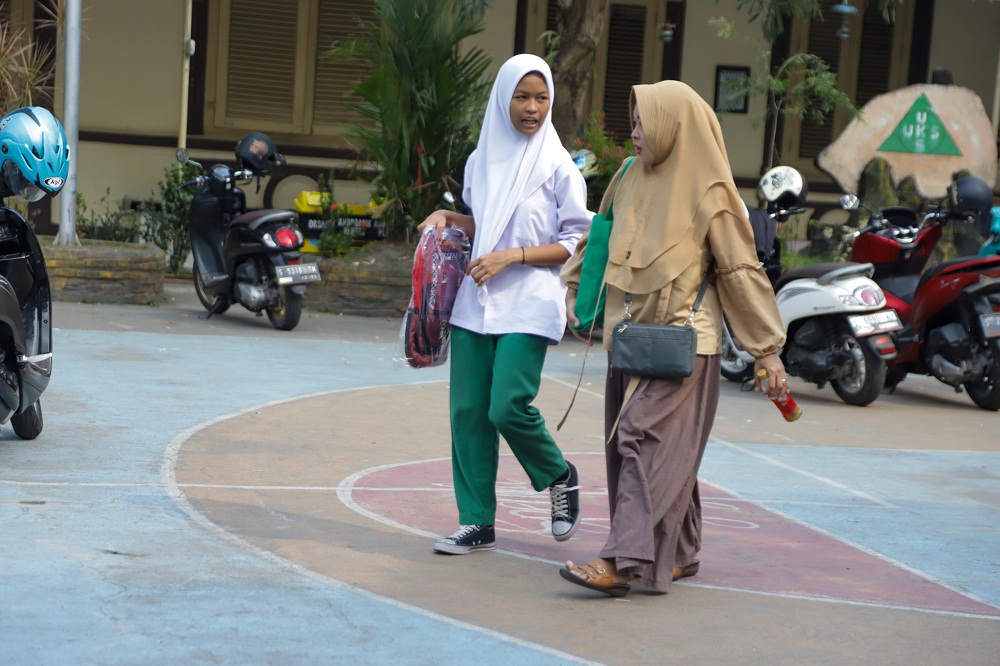 TERIMA: Seorang siswa didampingi orang tua usai menerima bantuan tas.