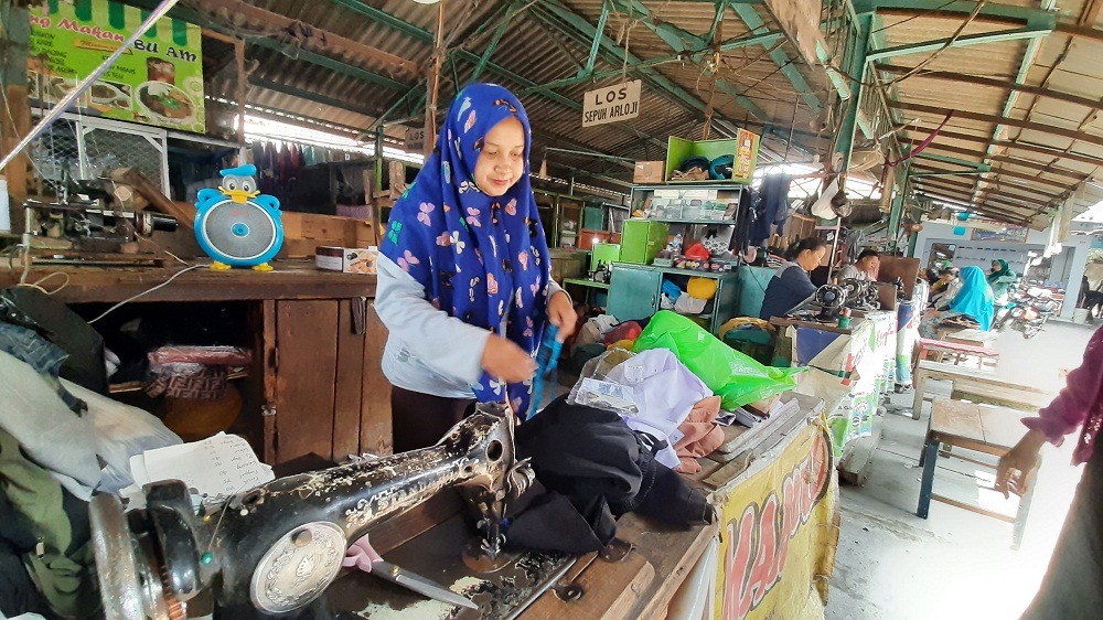 HARUS PAS: Titin, salah satu penjahit di Pasar Tanjung Anyar Kota Mojokerto sedang mengukur ukuran seragam siswa baru, kemarin.