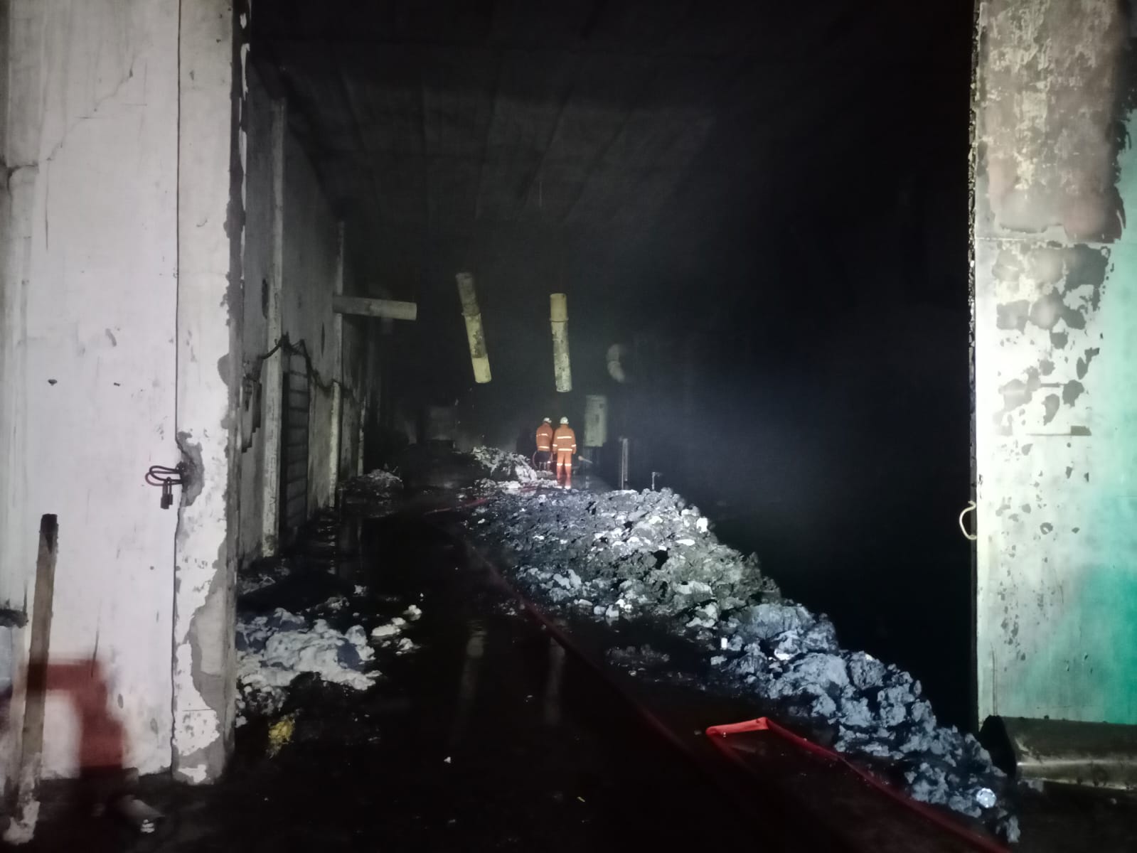 PENANGANAN: Petugas melakukan upaya pemadaman dan memasang garis polisi di ruang produksi UD Merak Utama Gloves, Jalan Raya Desa Perning, Kecamatan Jetis, Selasa (18/7) malam.