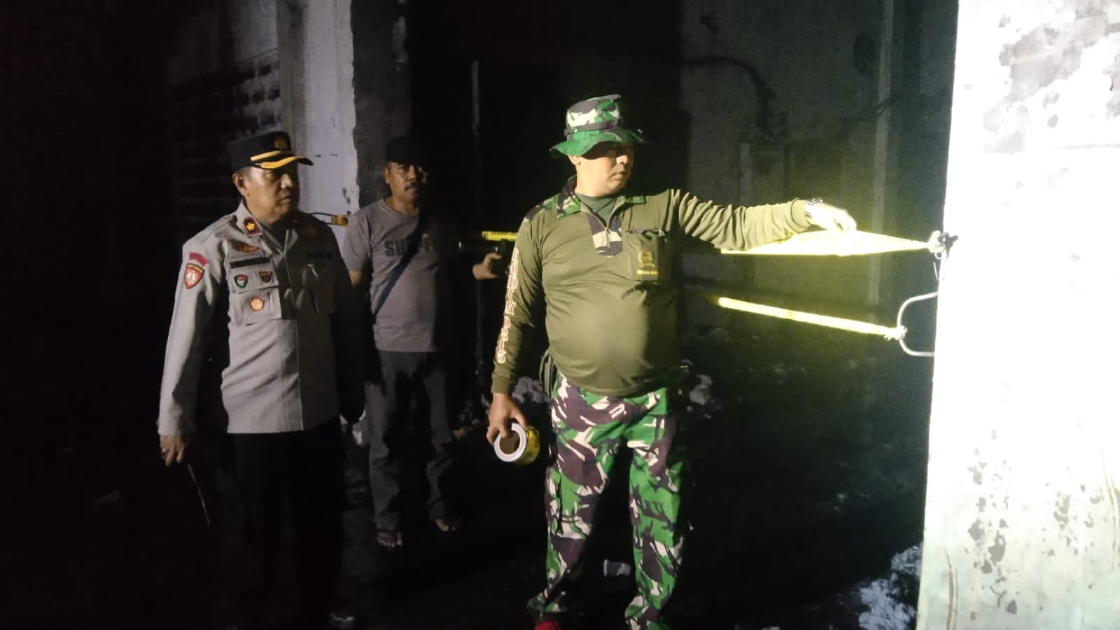 PENANGANAN: Petugas melakukan upaya pemadaman dan memasang garis polisi di ruang produksi UD Merak Utama Gloves, Jalan Raya Desa Perning, Kecamatan Jetis, Selasa (18/7) malam.