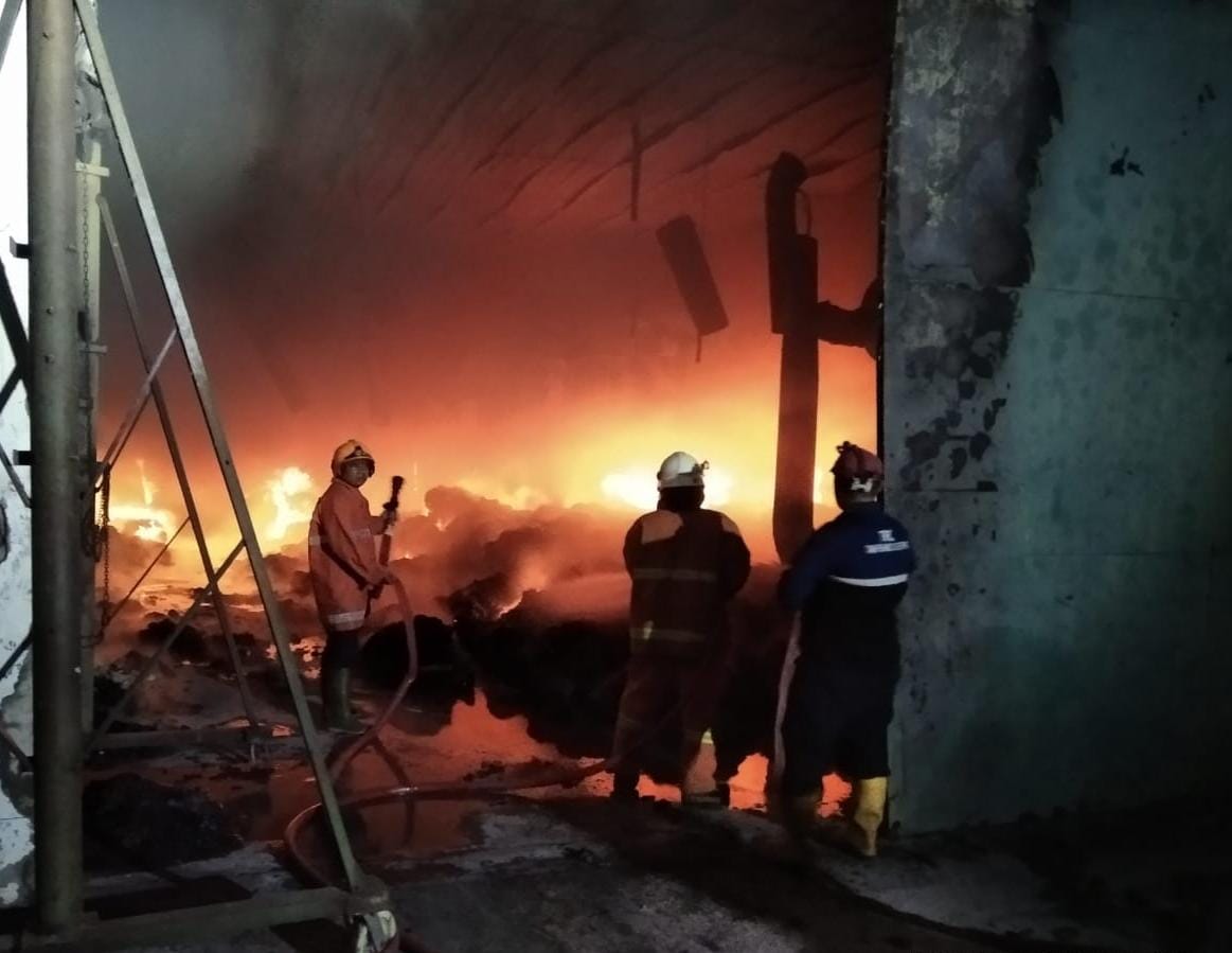 PENANGANAN: Petugas melakukan upaya pemadaman dan memasang garis polisi di ruang produksi UD Merak Utama Gloves, Jalan Raya Desa Perning, Kecamatan Jetis, Selasa (18/7) malam.