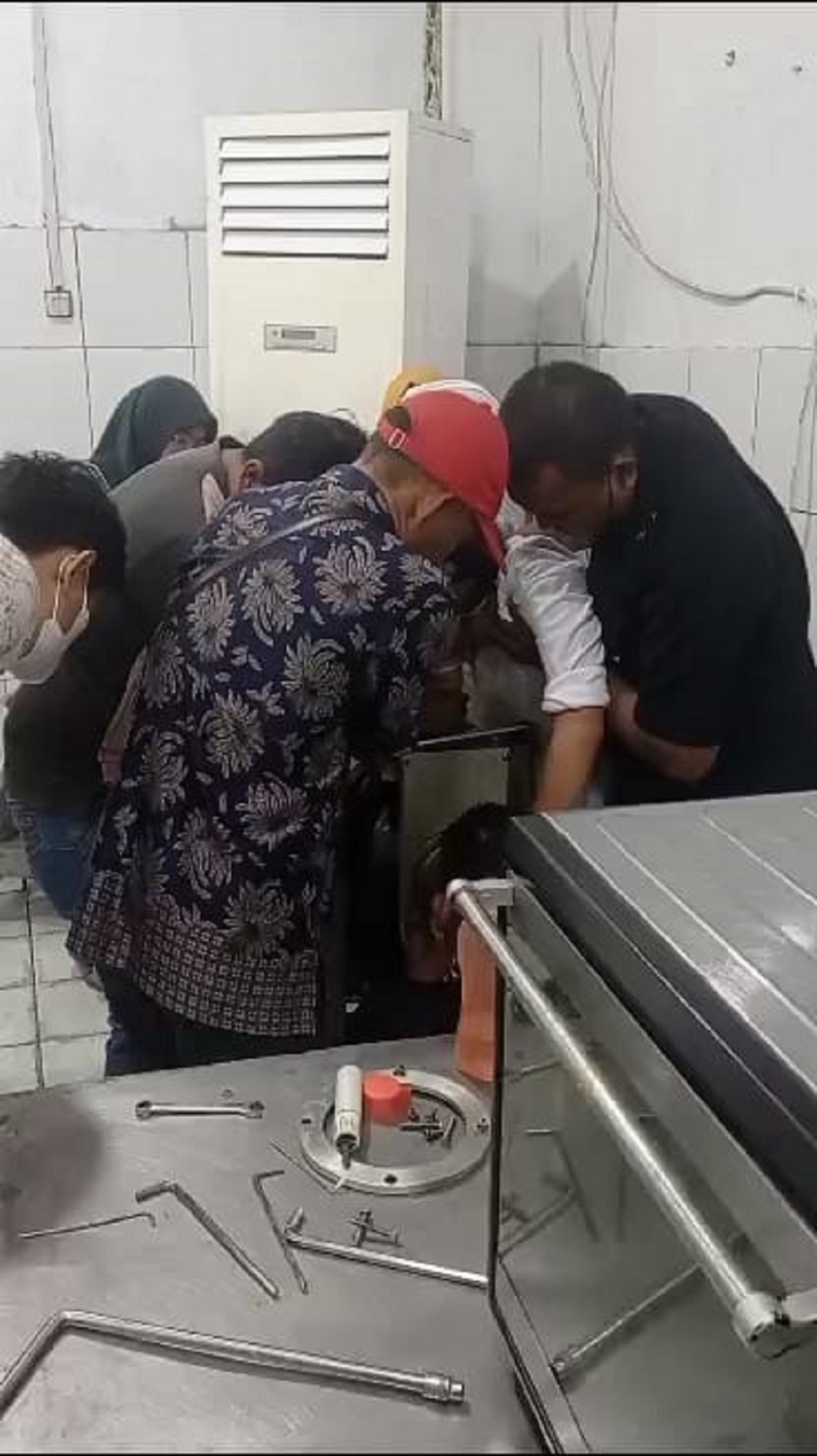 UPAYA EVAKUASI: Petugas berupaya mengevakuasi tangan korban secara manual setelah terjepit mesin penggiling. Korban akhirnya dilarikan ke rumah sakit bersama mesin.