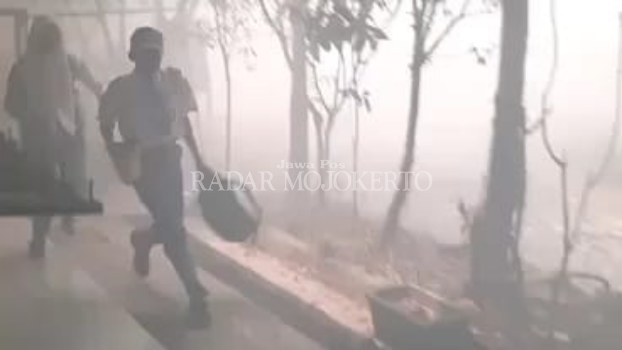 PANIK: Sejumlah siswa SMKN 1 Mojoanyaf berlarian di tengah kepulan asap kebakaran lahan di area kompleks sekolah, Senin (21/8).