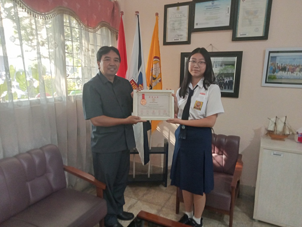 BERPRESTASI: Kepala SMP TNH Blasius Paimun, S.Pd memberikan apresiasi kepada Janice Deveneny Siem yang berhasil menyabet gelar runner up pada ajang Olimpiade Sains Internasional.