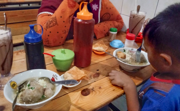 NIKMAT: Pelanggan dewasa hingga anak-anak lahap menikmati seporsi bakso telur dan segelas es di warung bakso Pak Yadi.