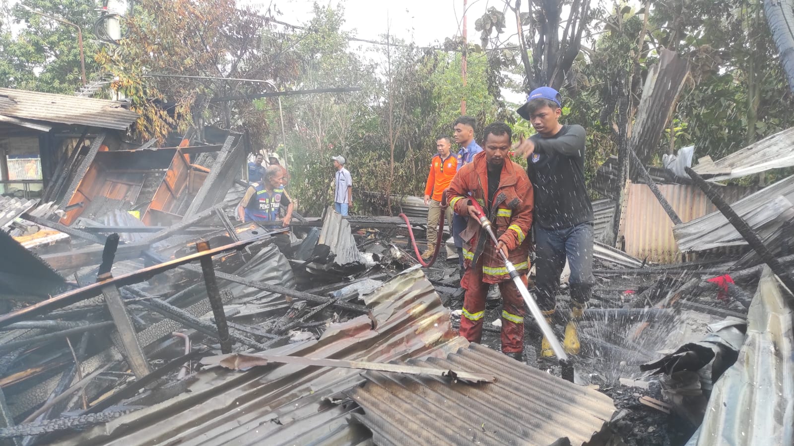 HANGUS: Petugas pemadam melakukan pembasahan rumah dan warung yang porak poranda dan hangus akibat terbakar hebat, Selasa (19/9).