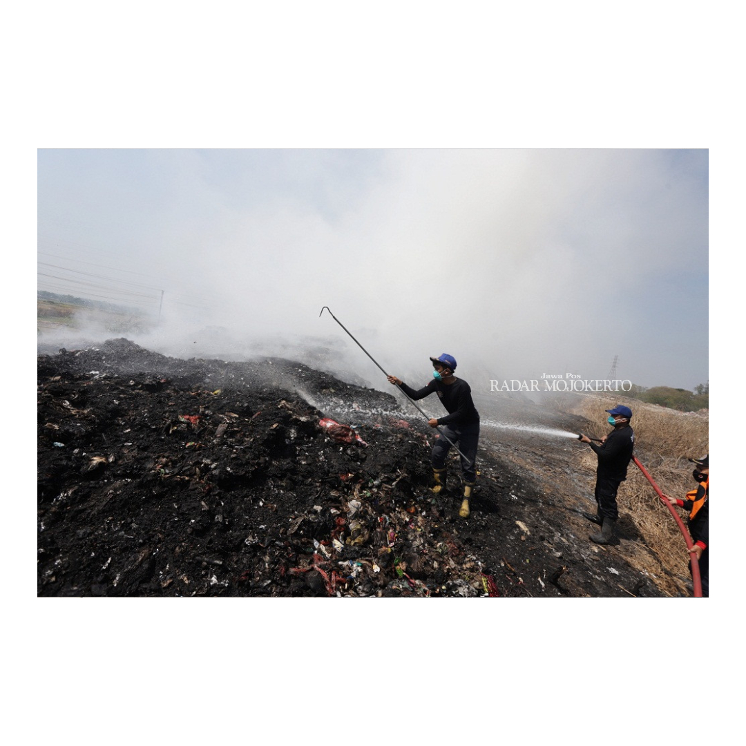 TERBAKAR LAGI: Petugas memadamkan api yang kembali membakar gunungan sampah di TPA Randegan Kota Mojokerto, kemarin.