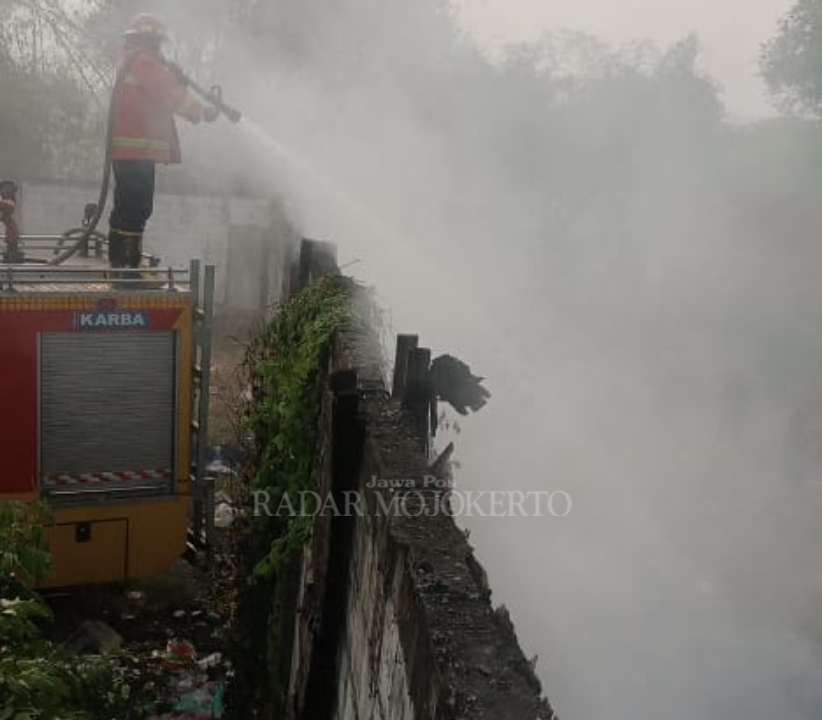 PEMBASAHAN: Petugas Damkar BPBD Kabupaten Mojokerto melokalisir api yang membakar gudang rosokan di Dusun/Desa Pekukuhan, Kecamatan Mojosari, Sabtu (30/9) sore.
