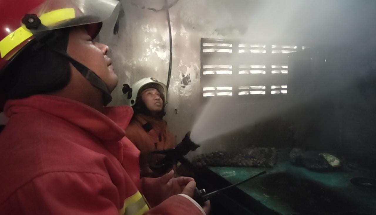 PEMADAMAN: Petugas PMK menyemprotkan  air ke ruang genset toko busana muslim yang terbakar di Sooko, Selasa (3/10).
