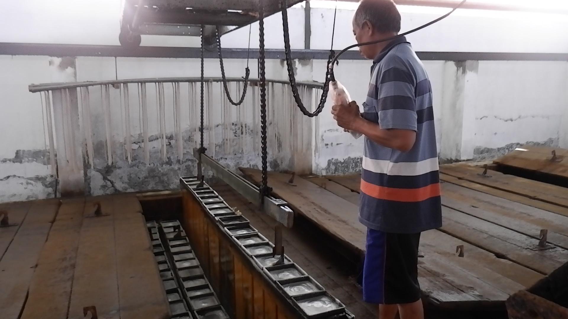 TELATEN: Pekerja tampak mengeluarkan cetakan berisi es balok dari pendinginan menggunakan bantuan mesin penarik, Rabu (11/10).