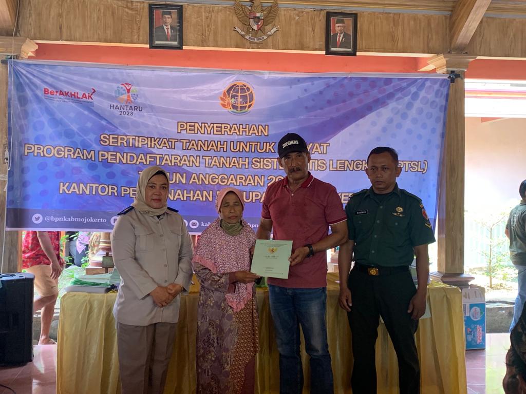 PENYERAHAN: Kades Domas Slamet Purwanto bersama perwakilan ATR/BPN Kabupaten Mojokerto menyerahkan sertifikat tanah PTSL.