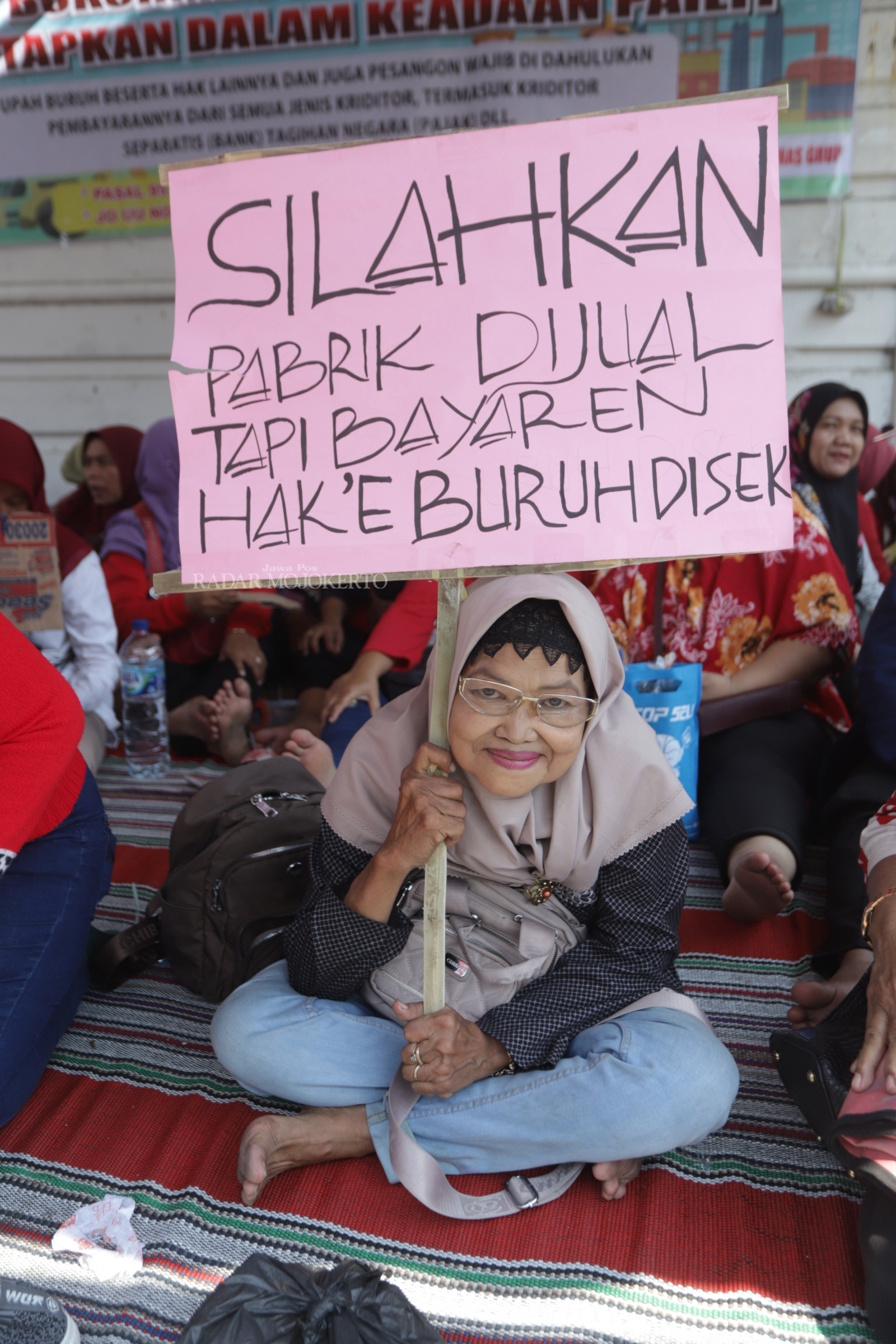 TUNTUT HAK: Salah satu pengunjuk rasa membawa poster berisikan tuntutan hak pesangon. Mantan buruh pabrik rokok Bokor Mas beraksi damai di depan pabrik di Jalan Pahlawan Kota Mojokerto, Rabu (8/11).