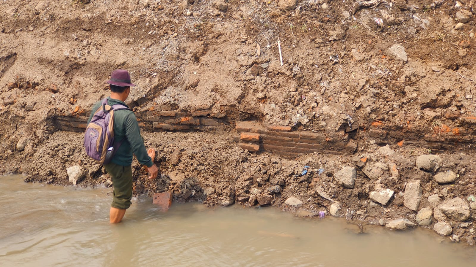 TEMUAN: Juru pelihara situs kumitir menunjukkan struktur bata kuno era Majapahitan yang ditemukan di tanggul sungai sisi selatan situs.