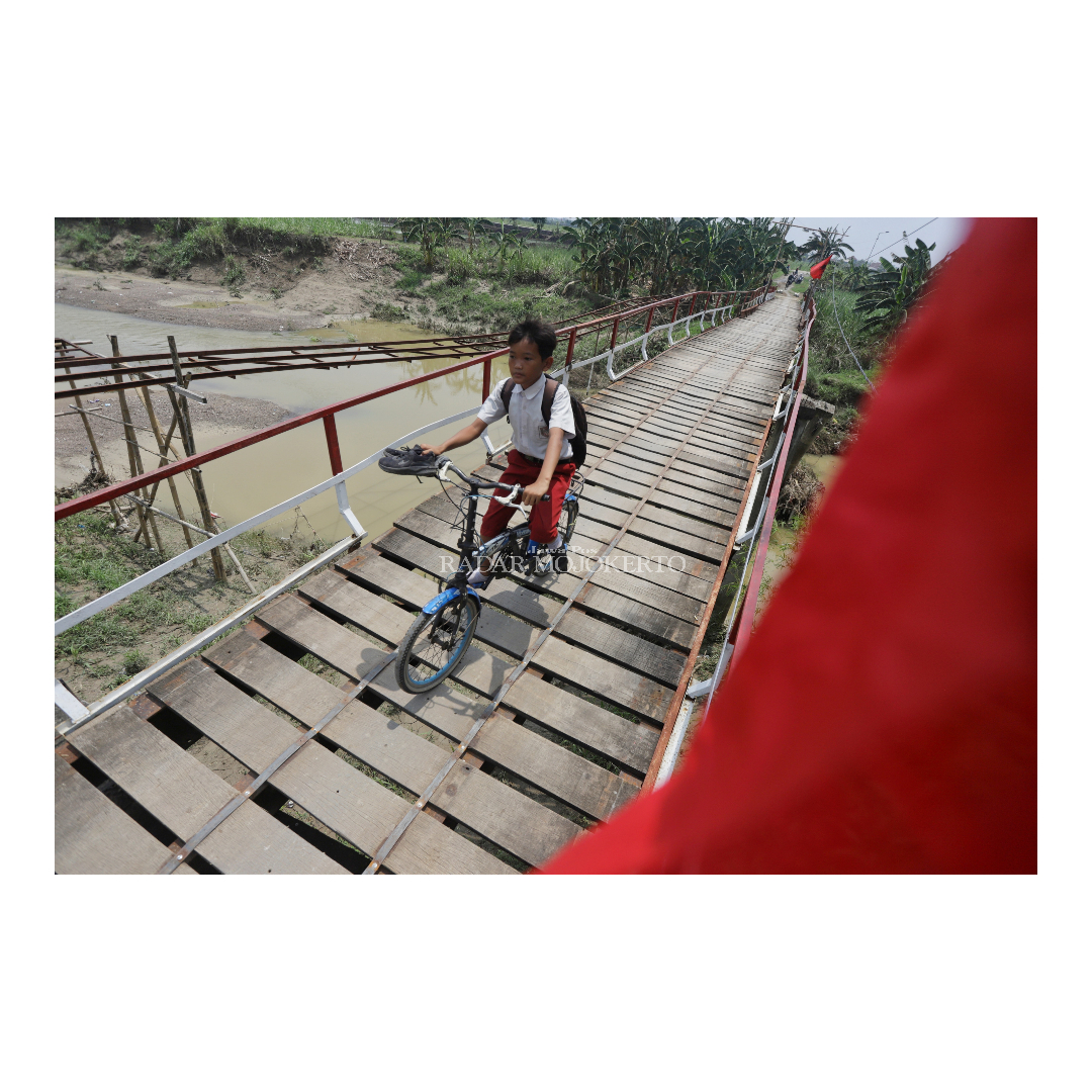 BERBAHAYA: Siswa SD di Dusun Talunbrak Desa Talunblandong bersepeda melintasi jembatan yang rusak akibat dihantam derasnya air sungai Lamong beberapa tahun lalu.