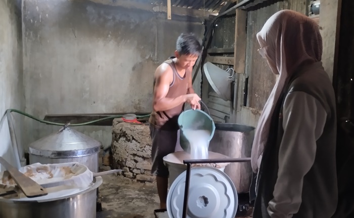 TELATEN: Salah satu karyawan sedang merebus air kelapa di panci berukuran besar untuk dijadikan bahan dasar nata de coco.