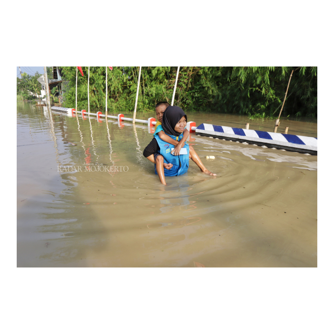 BANJIR SEPINGGANG: Relawan menggendong anak  menembus banjir di Dusun Klanting Desa Pulorejo Dawarblandong, Jumat (8/12).