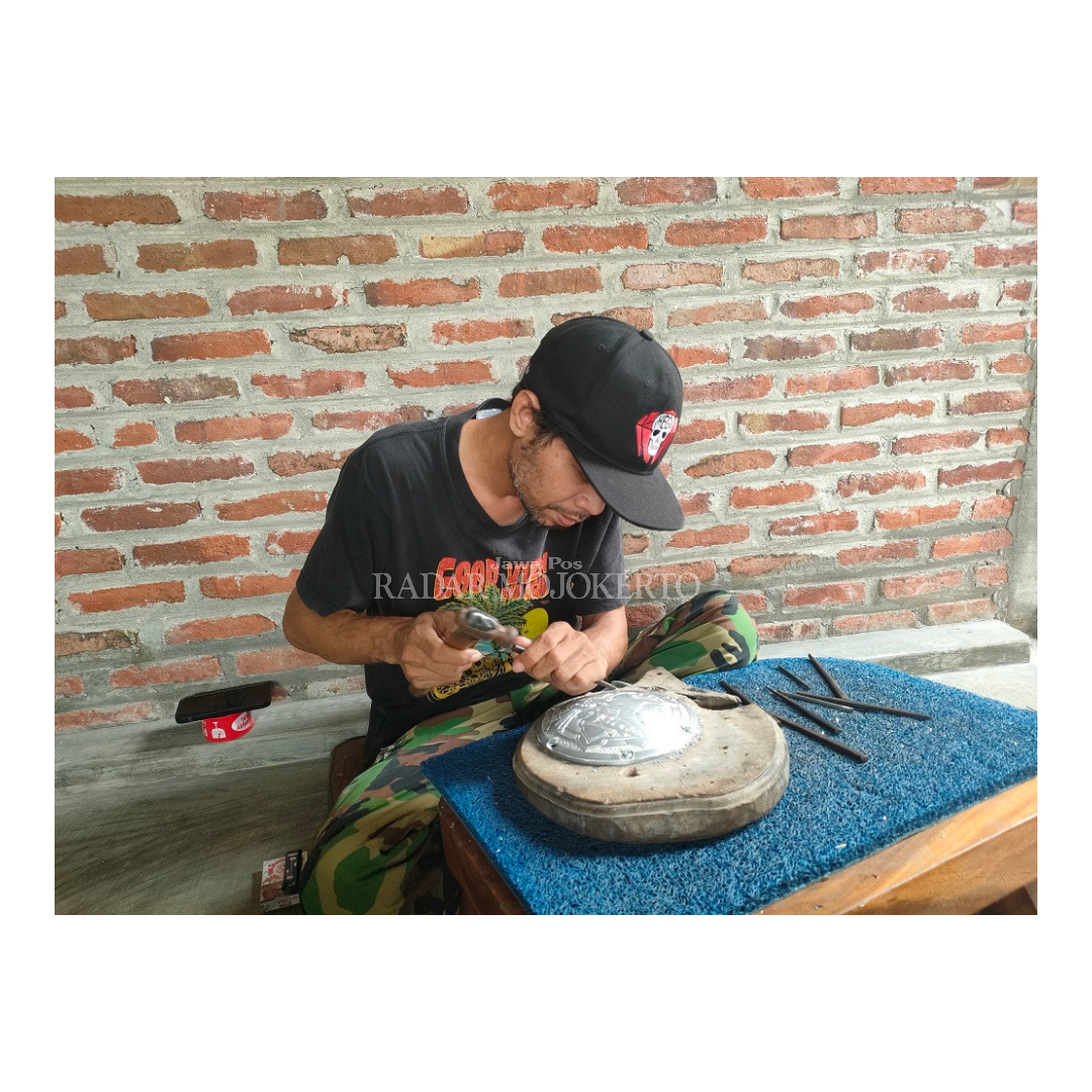 TELATEN: David Mardiono, eks seniman patung yang banting setir menekuni kerajinan metal engraving motor custom, di Dusun Jatipasar, Desa Watesumpak, Kecamatan Trowulan.