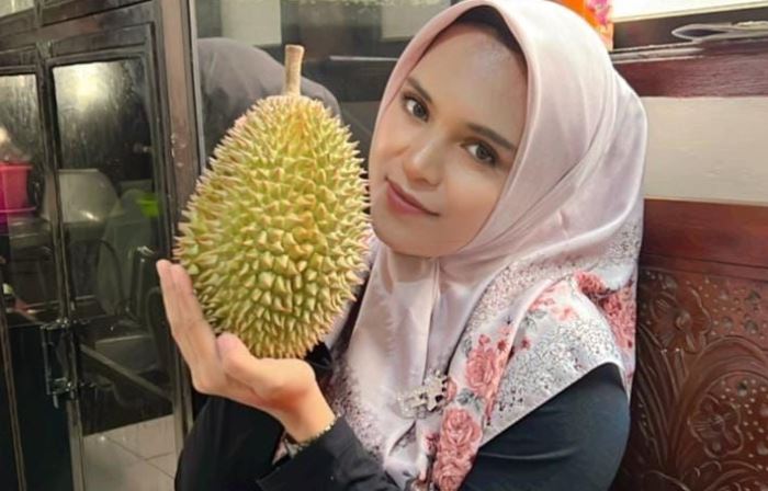 MENGGODA: Eka Nur Oktaviana, pedagang durian Desa Duyung, Kecamatan Trawas, menunjukkan durian jenis lokal. (foto Moch. Chariris)