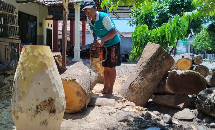TETAP EKSIS: Pardan menyiapkan kayu nangka untuk dijadikan alat musik kendang di halaman rumahnya, Dusun Pakis Kulon, Desa Pakis, Kecamatan Trowulan. (foto Nadya Azzahra for Radar Mojokerto)