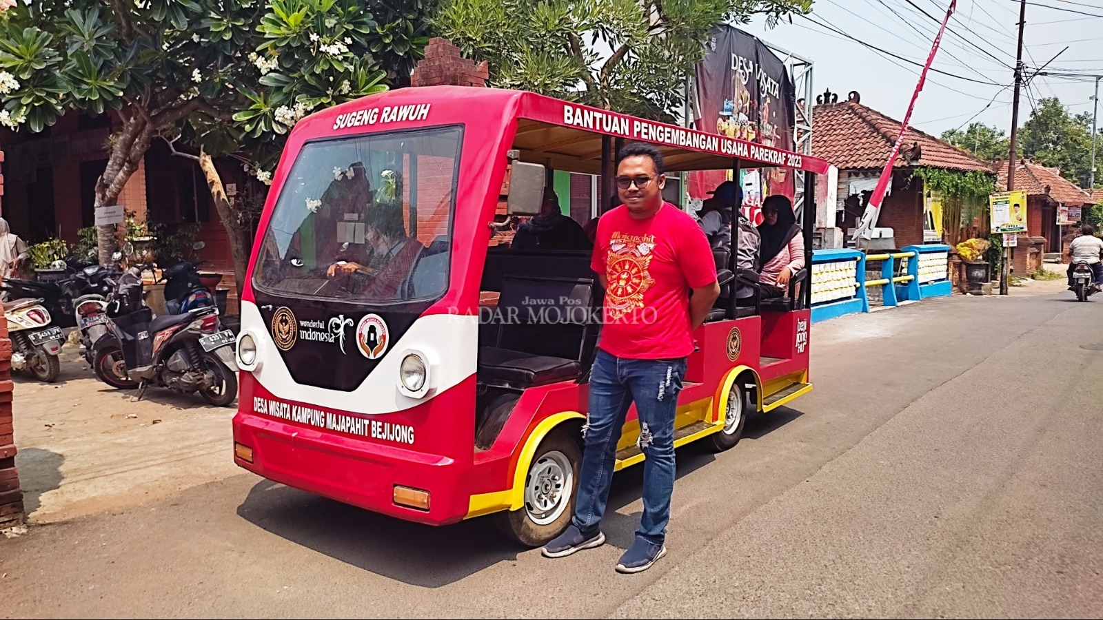 TRANSPORTASI WISATA: Kades Bejijong Pradana Tera Mardiatna mengantarkan tamu menaiki shuttle car untuk berkeliling di Kampung Majapahit.