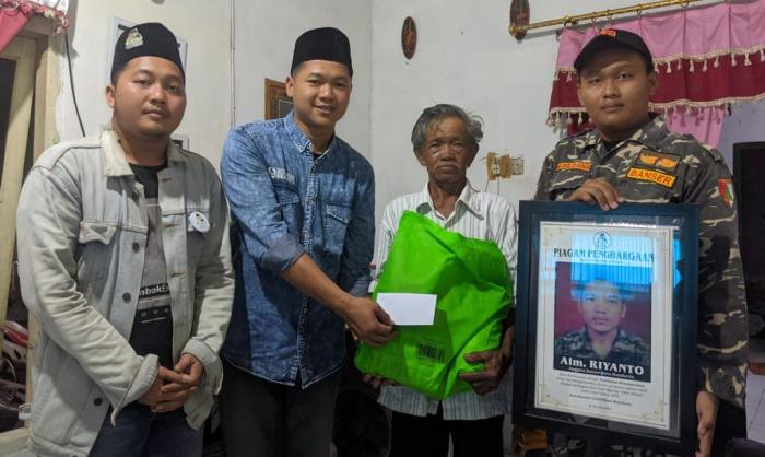 DIKENANG: Aktivis Jaringan Gusdurian Mojokerto bersama anggota Banser Kota Mojokerto menyerahkan penghargaan dan santunan kepada ayah Riyanto, Sukarmin.