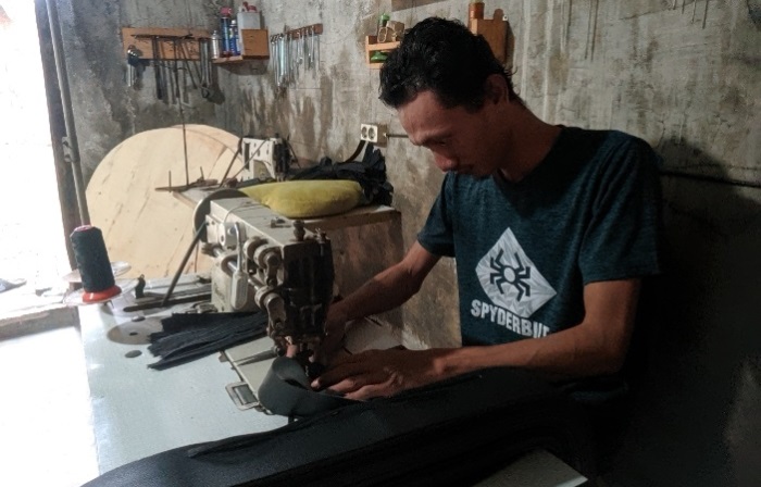 BERTAHAN: Dafit sedang memproduksi ikat pinggang di Desa Gemekan, Kecamatan Sooko, Kabupaten Mojokerto. (Foto Annisa Fadilah for Radar Mojokerto)