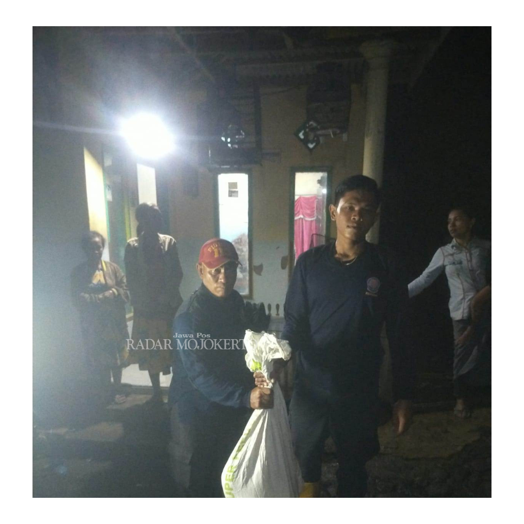 AGAR AMAN: Petugas Damkar menjinjing karung berisi seekor ular sanca kembang setelah dievakuasi dari rumah warga, Sabtu (27/1) malam.