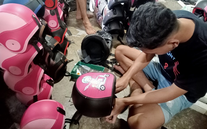 GELIAT: Karyawan mengerjakan proses pemasangan gesper pada helm anak, di Dusun/Desa Padangasri, Kecamatan Jatirejo, Kabupaten Mojokerto. (foto: Putri Fadiyah for Radar Mojokerto)