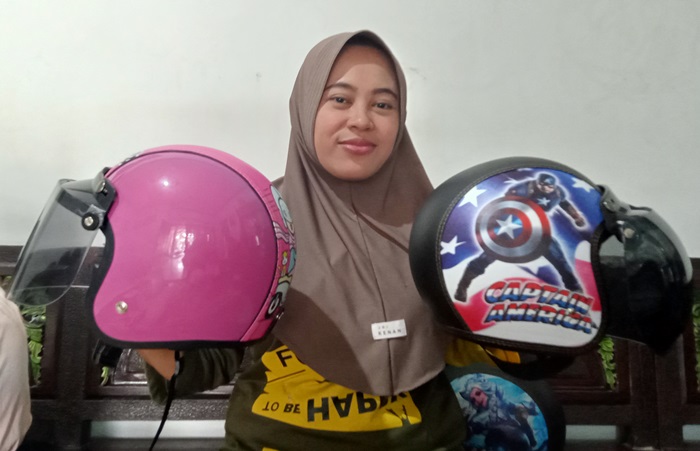 DIGANDERUNGI: Ma&rsquo;rifah menunjukkan produk helm superhero dan princess paling banyak diminati anak-anak, di Desa Padangasri, Kecamatan Jatirejo. (foto: Putri Fadiyah for Radar Mojokerto)