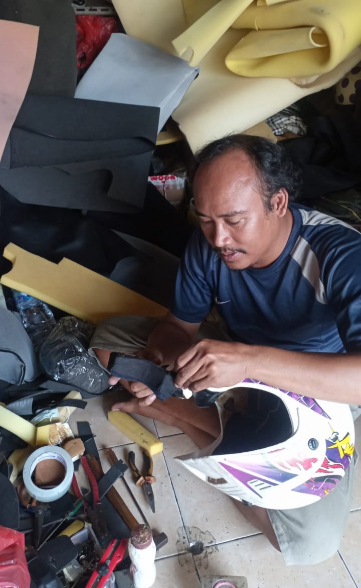 TELATEN: Muhammad Ardiansyah, menyervis helm di stan Pasar Kranggan No.12, Jalan Mojopahit, Kelurahan/Kecamatan Kranggan, Kota Mojokerto, (20/2/2024)