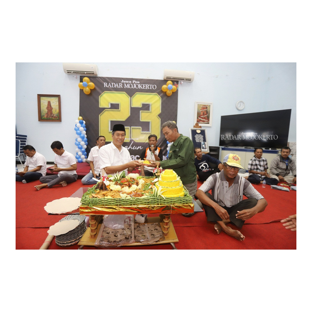 JALIN MITRA: Direktur Jawa Pos Radar Mojokerto M. Nur Kholis memberikan potongan tumpeng kepada agen koran terlama saat tasyakuran, kemarin.