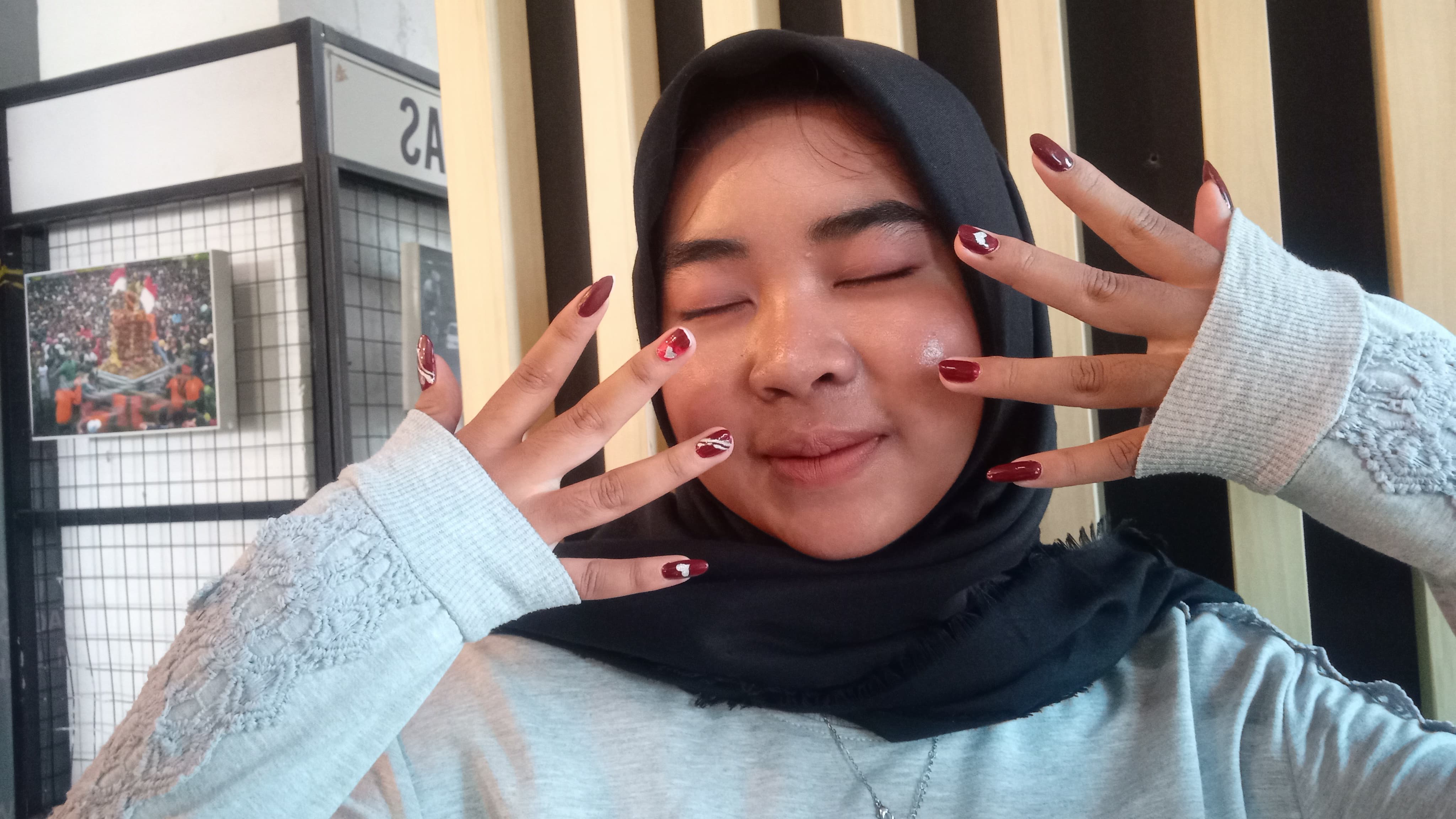 BERKILAU: Nur Hidayatul siswa asal Trowulan menggunakan lukisan nail art berwarna merah marun dengan glitter. (foto: Wilda Mifta dok for Radar Mojokerto)