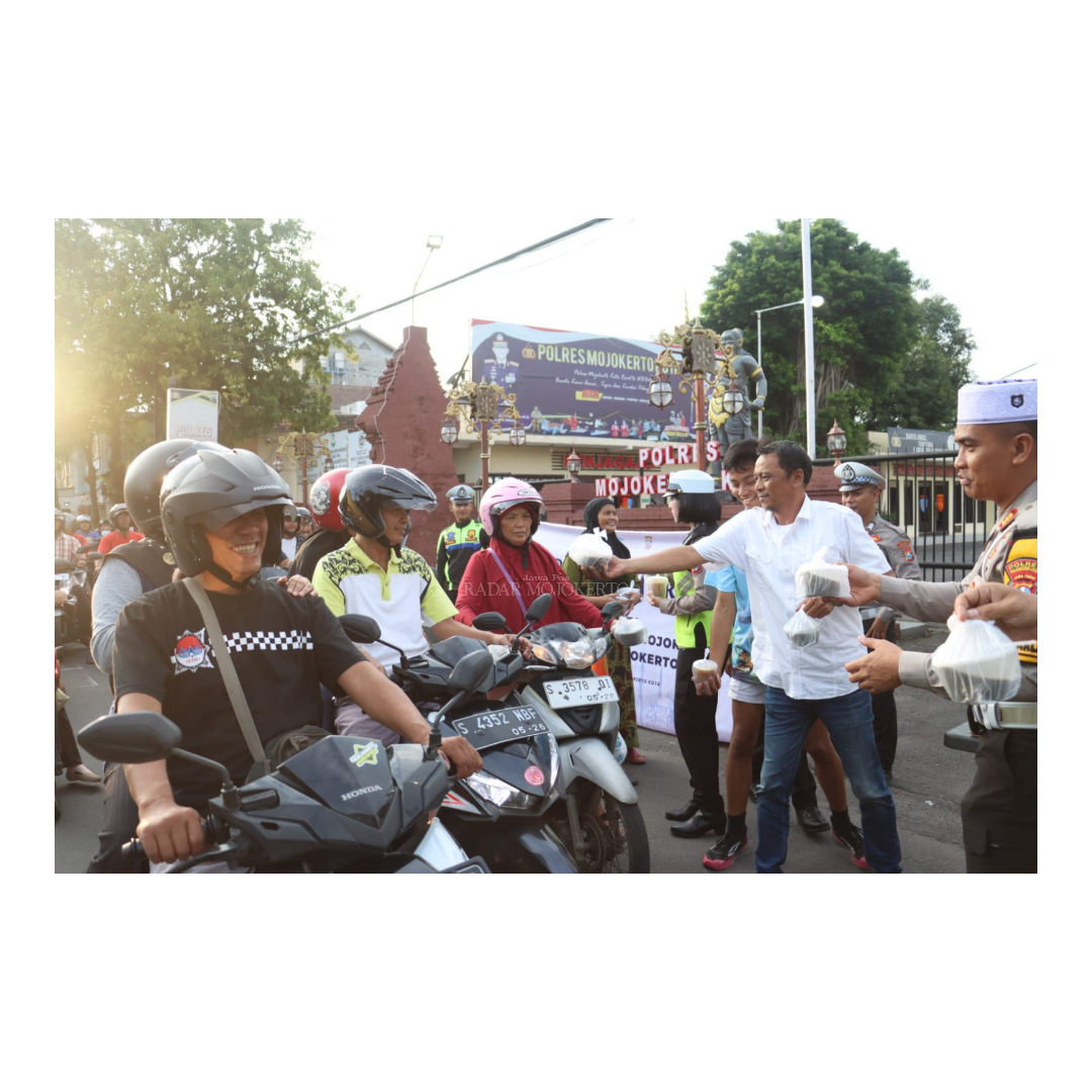 KETELADANAN: Kasatlantas Polres Mojokerto Kota, AKP Sudirman (kanan) bersama Manajer Event JPRM Arief Hikmawan (baju putih) membagikan takjil kepada pengguna jalan dan ojek online kemarin.