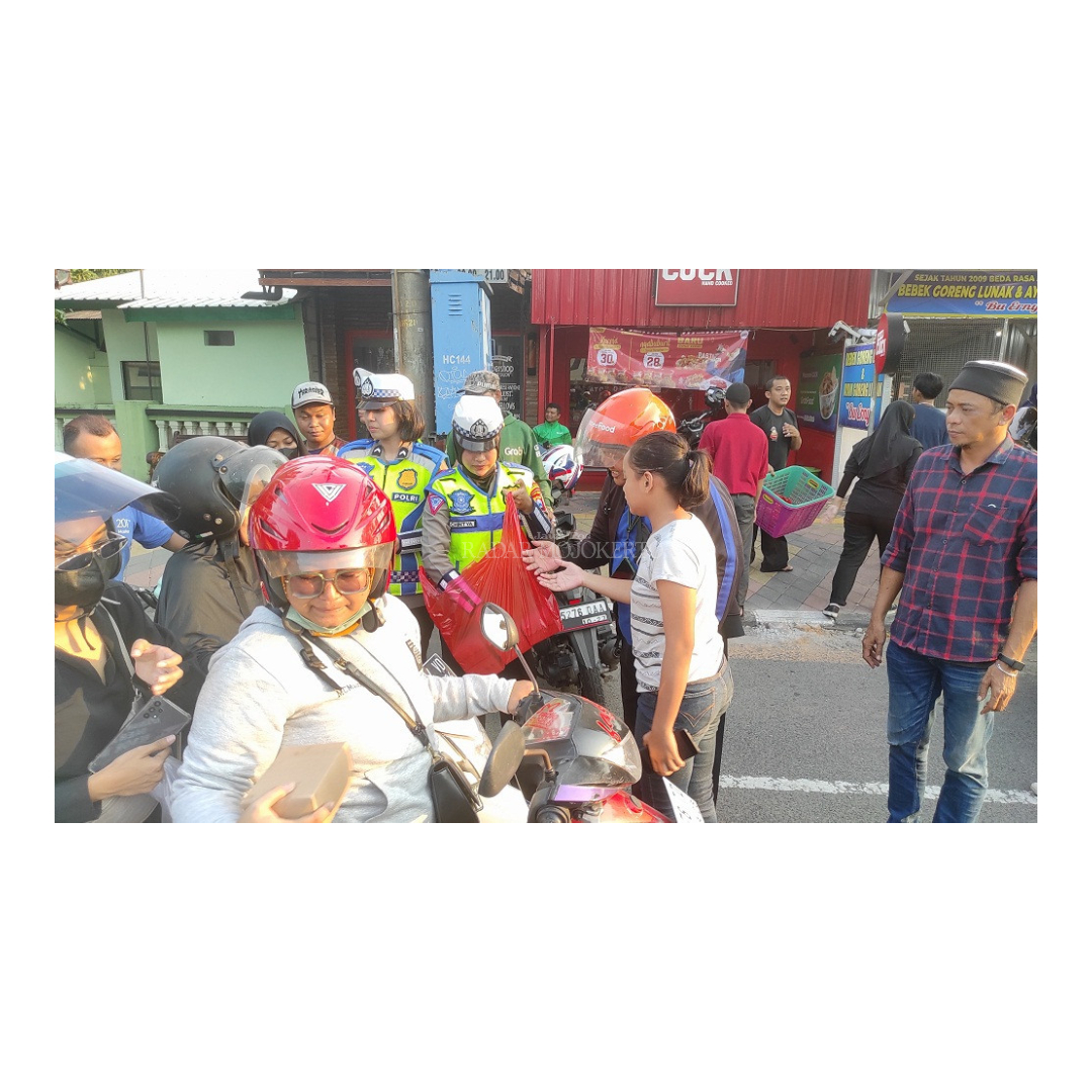 SALING BERBAGI: Anggota kepolisian dan Polwan membagikan takjil gratis kepada pengendara yang melintas di Jalan Bhayangkara kemarin.