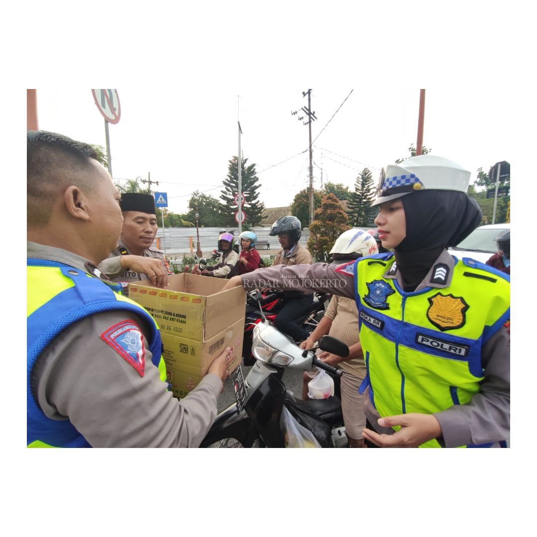 PEDULI: Anggota Satlantas Polres Mojokerto Kota membagikan takjil gratis ke pengguna jalan dan penjaga palang pintu di jalan Pahlawan Kota Mojokerto kemarin.
