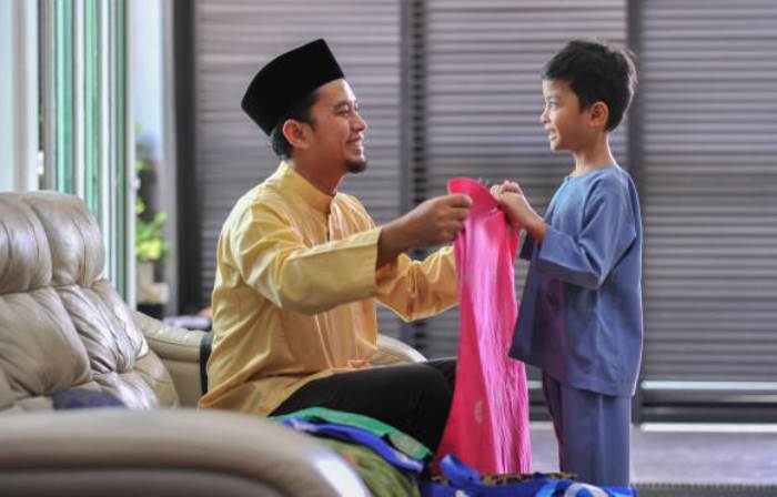 BAJU BARU: Seorang ayah memberikan baju baru kepada putranya agar dapat dikenakan saat hari Raya Idul Fitri. (foto: dok. Internet)