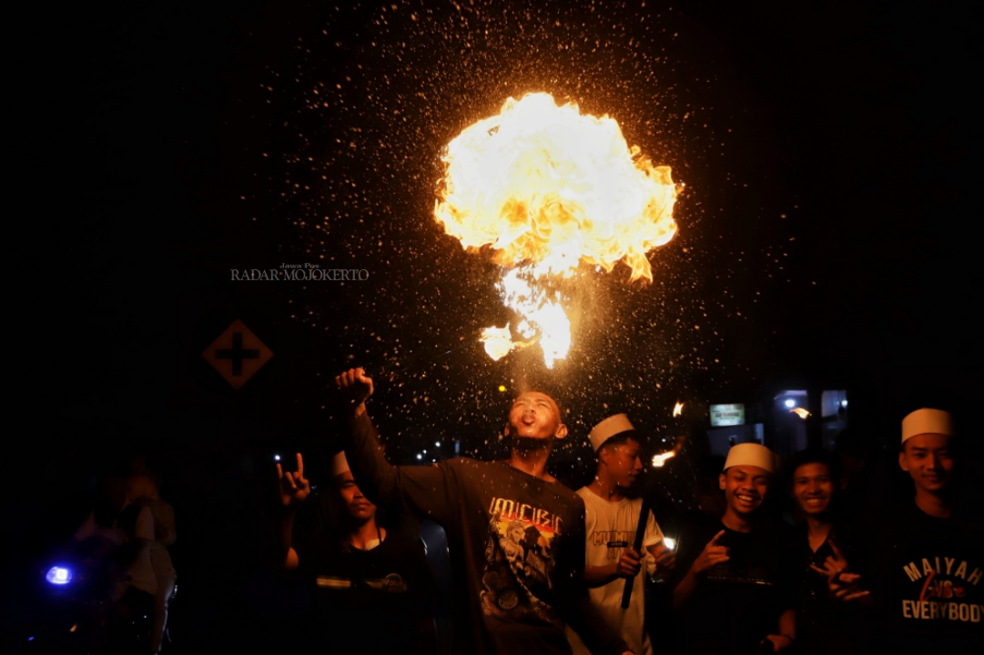 EKSPRESI: Warga Dawarblandong Kabupaten Mojokerto beratraksi ketika mengikuti pawai obor malam takbiran, Selasa (9/4/2024).
