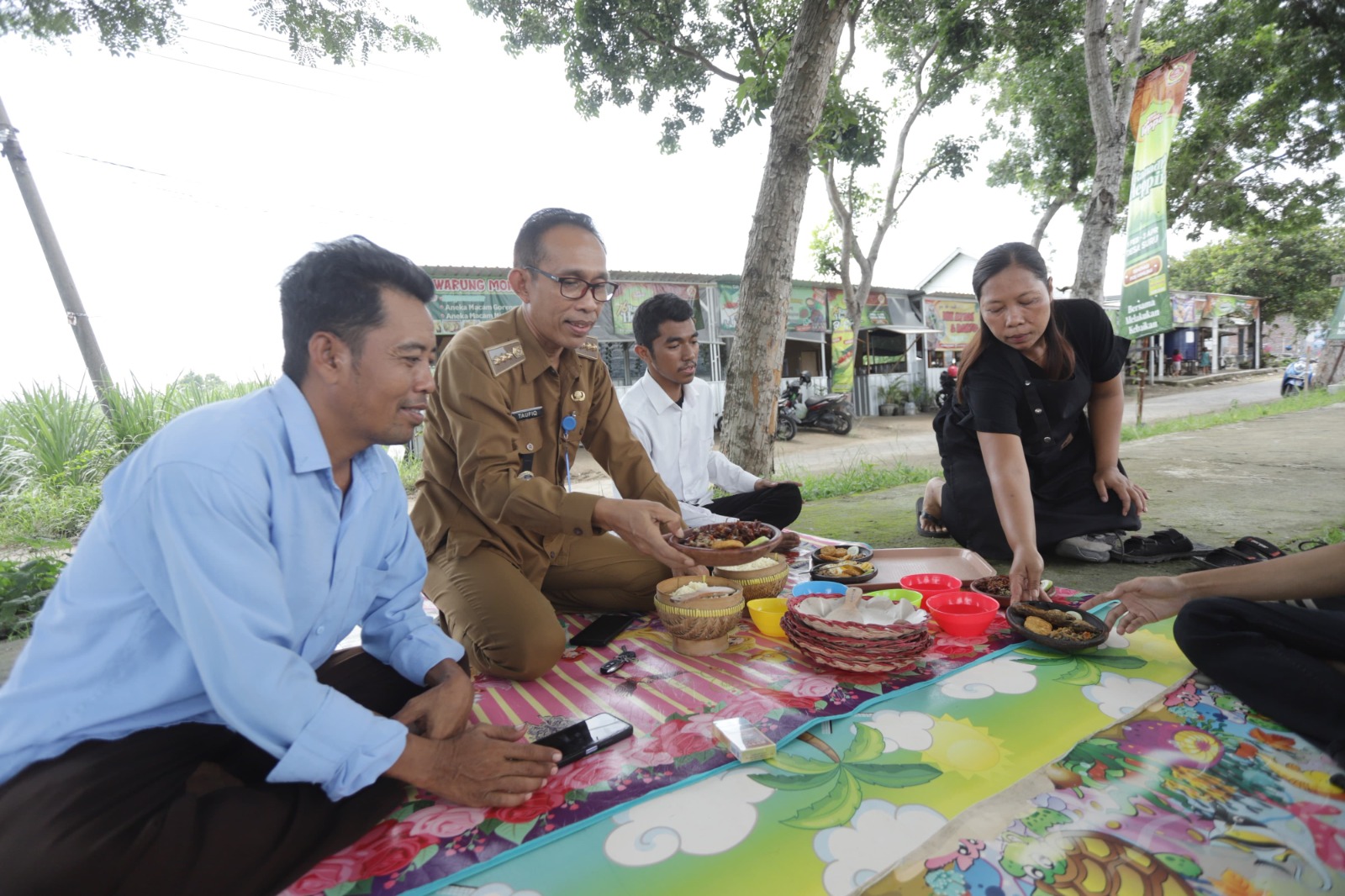IKON KULINER: Camat Dawarblandong Akhmad Taufiq (dua dari kiri) dan Kepala Desa Suru Suyono (kiri) menikmati menu belalang goreng olahan Fatmawati (kanan).
