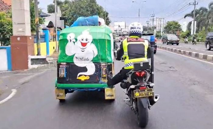 SEJAUH 8 KM: Petugas Satlantas Polres Mojokerto mendorong bajai dari Trowulan menuju Pos Polisi Jampirogo, Sooko, Mojokerto. (foto: Moch. Chariris)