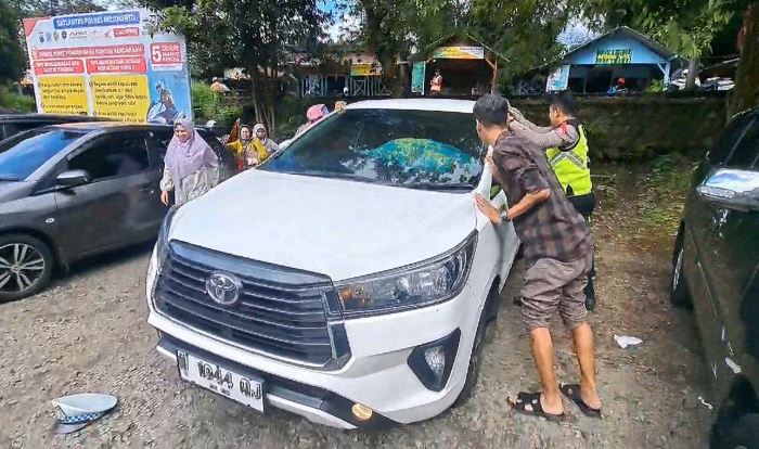 TERTIDUR: Keluarga dibantu polisi dan wisatawan menggoyang mobil Toyota Innova Reborn dalam kondisi terkunci dari dalam, di kawasan Wisata Sendi, Pacet, Mojokerto, Sabtu (13/4).(foto: Moch. Chariris)