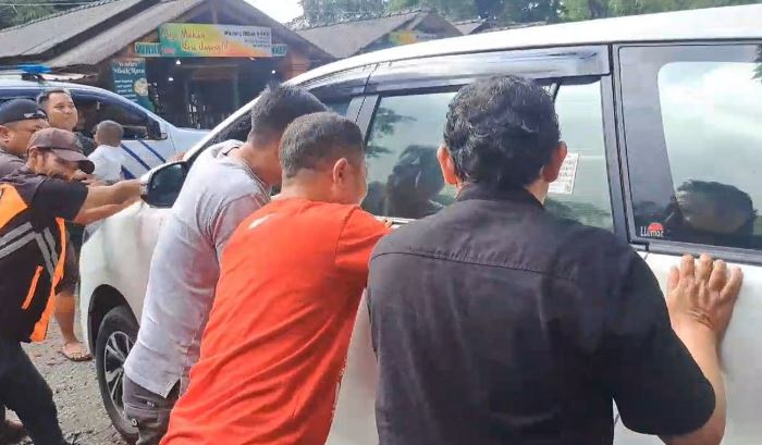 DIGEDOR: Sugik, pemilik mobil (kaus oranye) menggedor kaca mobil untuk membangunkan putranya dalam mobil yang dalam kondisi terkunci. (foto: Moch. Chariris)